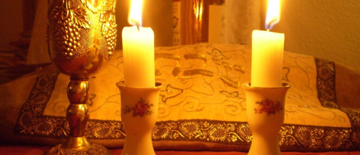 Shabbat candles, a kiddush cup, and covered challah