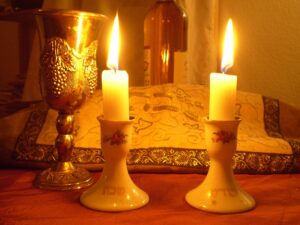 Shabbat candles, a kiddush cup, and covered challah