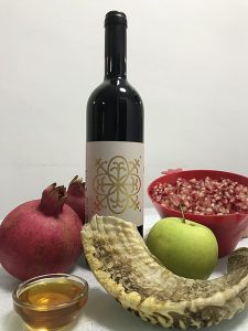 Rosh Hashanah symbols: a bottle of wine, a shofar, pomegranates, apples and honey